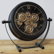 Stylish desktop timepiece with black casing, gold-accented rotating cogs, and modern mechanical design, 28cm high by 30cm wide by 11cm deep, 1.22kg; operates on 3 AA batteries (not included).