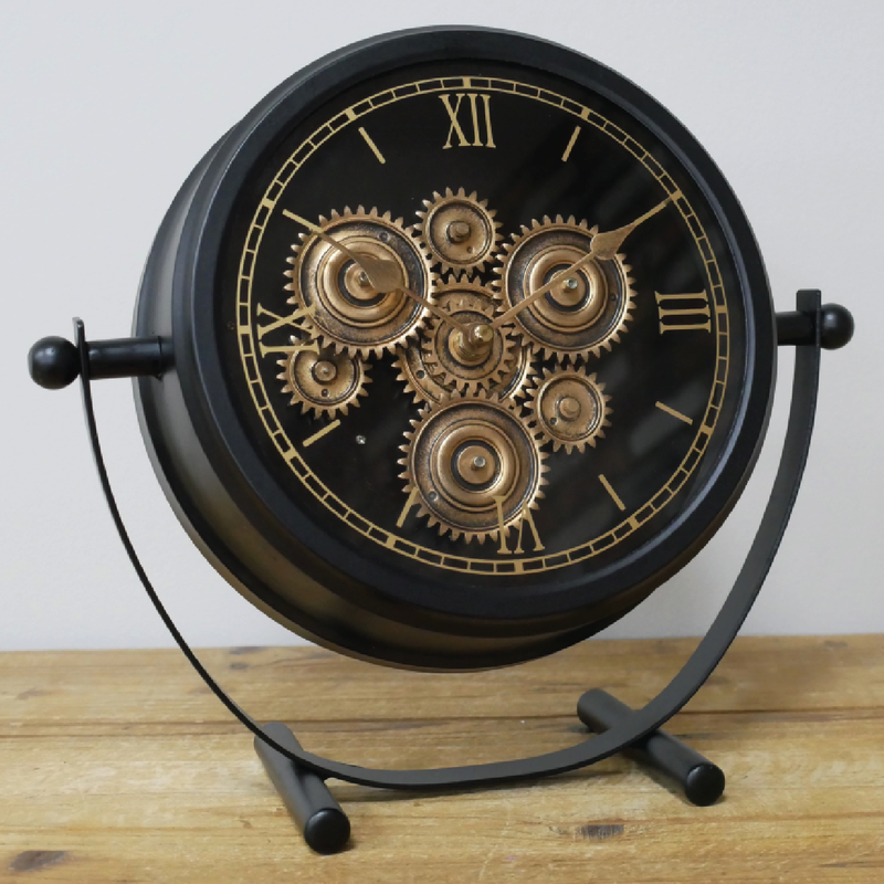 Stylish desktop timepiece with black casing, gold-accented rotating cogs, and modern mechanical design, 28cm high by 30cm wide by 11cm deep, 1.22kg; operates on 3 AA batteries (not included).