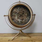Elegant gold-finished tripod desk clock with exposed gears and a sculptural three-legged base, 57 × 48 × 23cm, total weight 3kg.