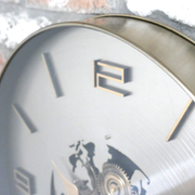 Decorative wall clock featuring a world map design, silver background, gold numerals, and functional cog details, dimensions 60cm H × 60cm W × 8cm D, weight 5kg.