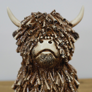 Medium-sized sitting Highland cow ornament, 18cm high, 12cm wide, 13cm deep, weighing 0.83kg, ideal for modern or rustic interiors.
