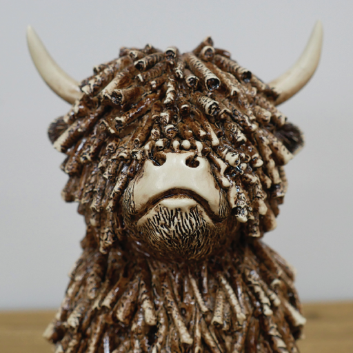 Medium-sized sitting Highland cow ornament, 18cm high, 12cm wide, 13cm deep, weighing 0.83kg, ideal for modern or rustic interiors.