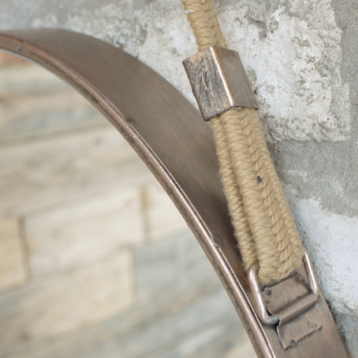 Decorative circular mirror in rose gold finish featuring a leather or fabric hanging strap, dimensions 47cm H × 47cm W × 4cm D, weight 2kg.